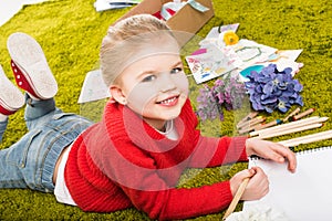 smiling  little child drawing with color pencils on green