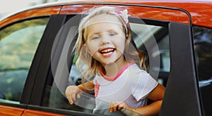 Smiling little child passenger sitting in a red car