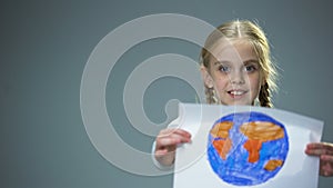 Smiling little child showing Earth picture into camera, global peace concept