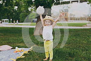 Smiling little cute child baby girl with basket play and have fun, spreading hands on green grass lawn in park. Mother