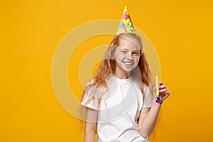 Smiling little ginger kid girl 12-13 years old in white t-shirt, birthday hat isolated on yellow background children