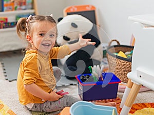 Smiling little girl 2 years old sitting on the carpet, playing with toys and holding markers. Children's room, kindergarten