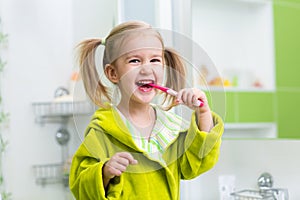 Smiling little girl brushing teeth in bathroom