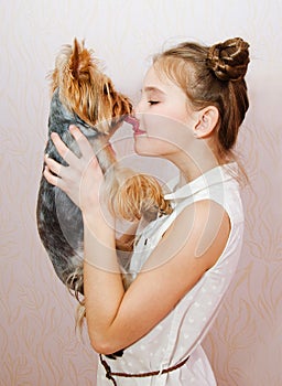 Smiling little girl child schoolgirl holding and playing with pet dog yorkshire terrier