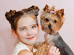 Smiling little girl child schoolgirl holding and playing with pet dog yorkshire terrier