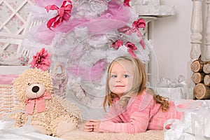 Smiling little girl at christmas tree indoors