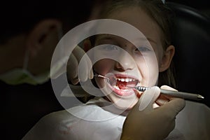 Smiling little girl in the dental office, getting her teeth checked by dentist