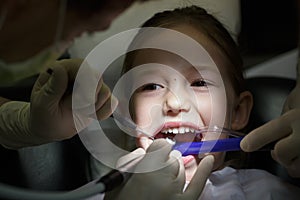 Smiling little girl in the dental office, getting her teeth checked by dentist