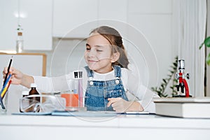 Smiling little girl doing home science project, reaching for crayons