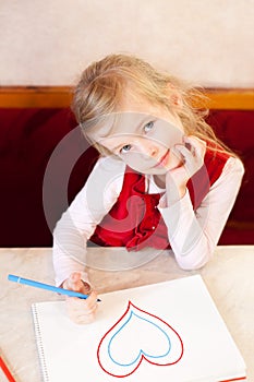 Smiling little girl draws heart. Valentine's Day