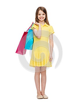 Smiling little girl in dress with shopping bags