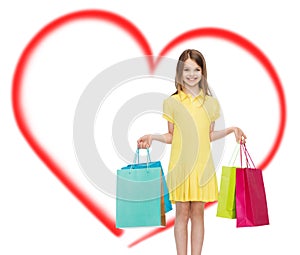 Smiling little girl in dress with shopping bags