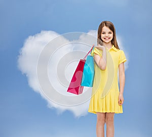 Smiling little girl in dress with shopping bags