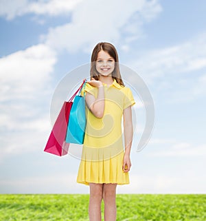 Smiling little girl in dress with shopping bags
