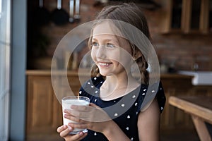 Smiling little girl drink delicious milk form glass