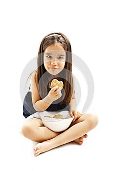 Smiling little girl eating cookie or biscuit.