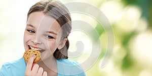 Smiling little girl eating cookie or biscuit