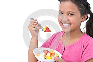 Smiling little girl eating fruit salad