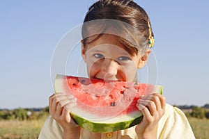 Smiling little girl eating watermelon