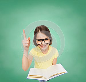 Smiling little girl in eyeglasses with book