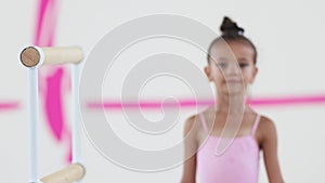 Smiling little girl gymnast walks to a handrail and looks in the camera