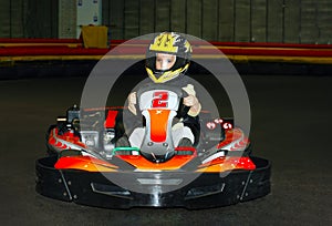 a the smiling little girl in a helmet in the go-kart on the karting track