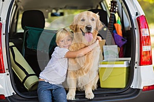 Smiling little girl with her dog in car trunk