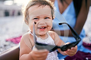 Smiling little girl holding big sunglasses in her hands