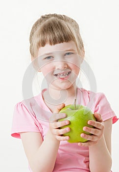 Smiling little girl holding a green apple