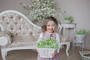 Smiling little girl holds a basket with flowers at hands