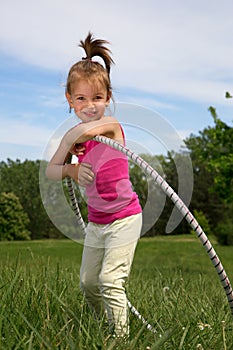 Smiling Little Girl With Hula Hoop Enjoying Beautiful Spring Day In The Park