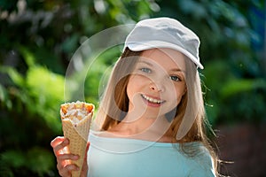 Smiling little girl with ice cream. Portrait of cute kid with blue eyes on nature background