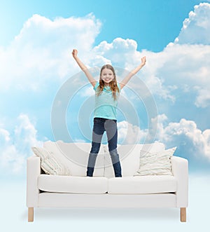 Smiling little girl jumping on sofa