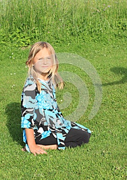 Smiling little girl kneeing on grass photo