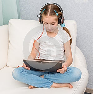 Smiling little girl listening something with headphones