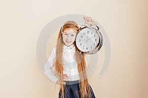 Smiling little girl with long hair holding big clock on neutral background. Time management, deadline, time to study, school