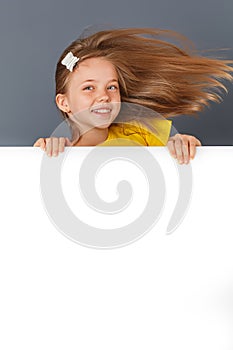 Smiling little girl looking behind a white board