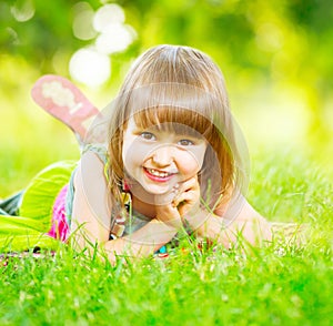 Smiling little girl lying on green grass