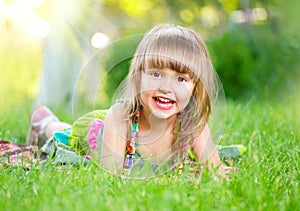 Smiling little girl lying on green grass