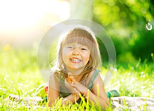 Smiling little girl lying on green grass