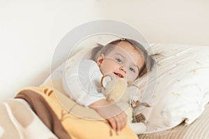 Smiling little girl lying on her bed hugging her favourite soft