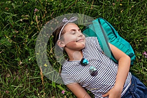 Smiling little girl lying with her eyes closed on grass