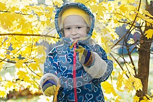 Smiling little girl outdoor portrait at yellow autumn shrubbery leaves background