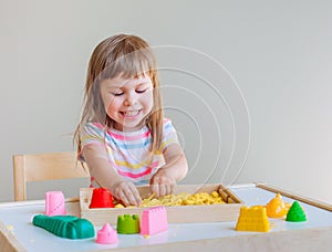 Smiling little girl playing with colorful kinetic sand