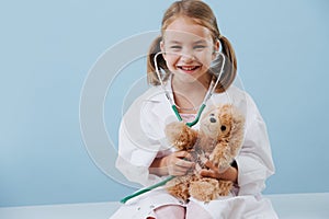Smiling little girl playing doctor, wearing long white robes with stethoscope