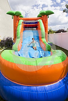 Smiling little girl playing on an inflatable slide bounce house outdoors