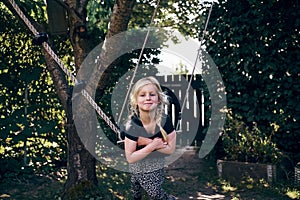 Smiling little girl playing on a tree swing outdoors