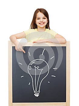 Smiling little girl pointing finger to blackboard