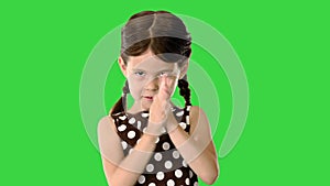 Smiling little girl in polka dot dress clapping her hands vigorously looking at camera on a Green Screen, Chroma Key.