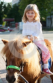 Smiling little girl on a pony